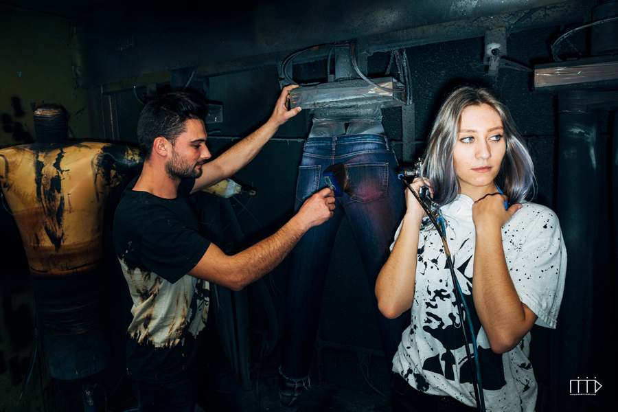 Denim innovation specialist working on trousers while model looks at the camera